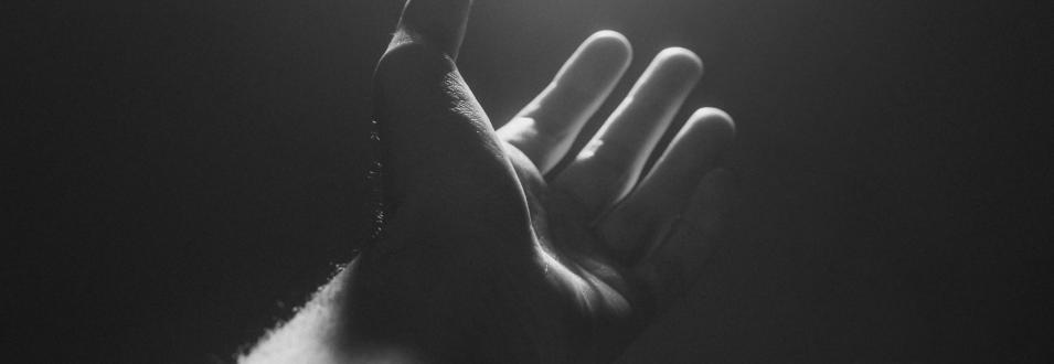 Schwarzweißaufnahme einer geöffneten Hand im Streiflicht